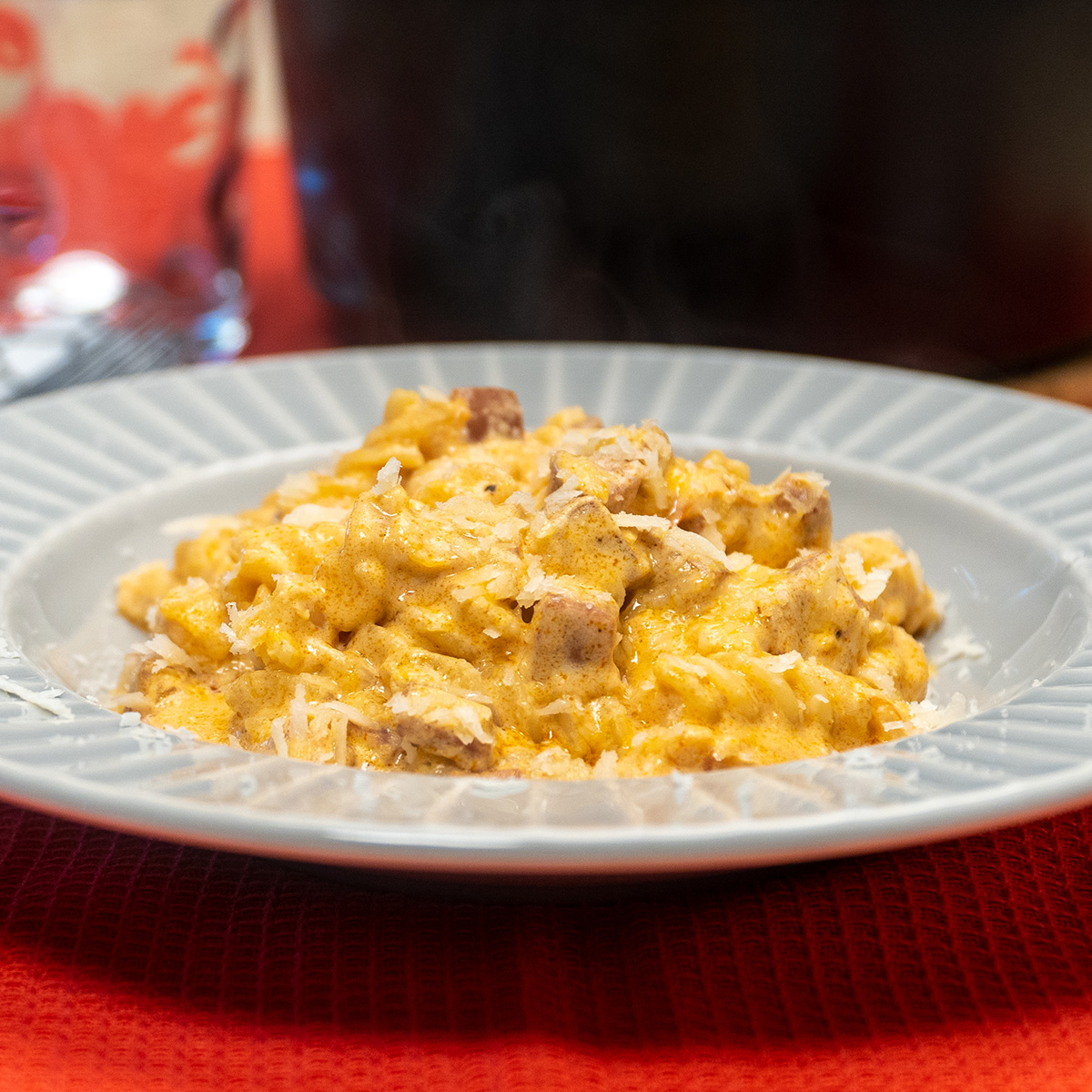 Empratamento macarrão cremoso com linguiça calabresa finalizada com queijo parmesão ralado por cima.