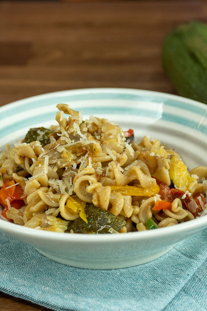 Empratamento macarrão integral com legumes assados finalizado com salsa picada e parmesão ralado.