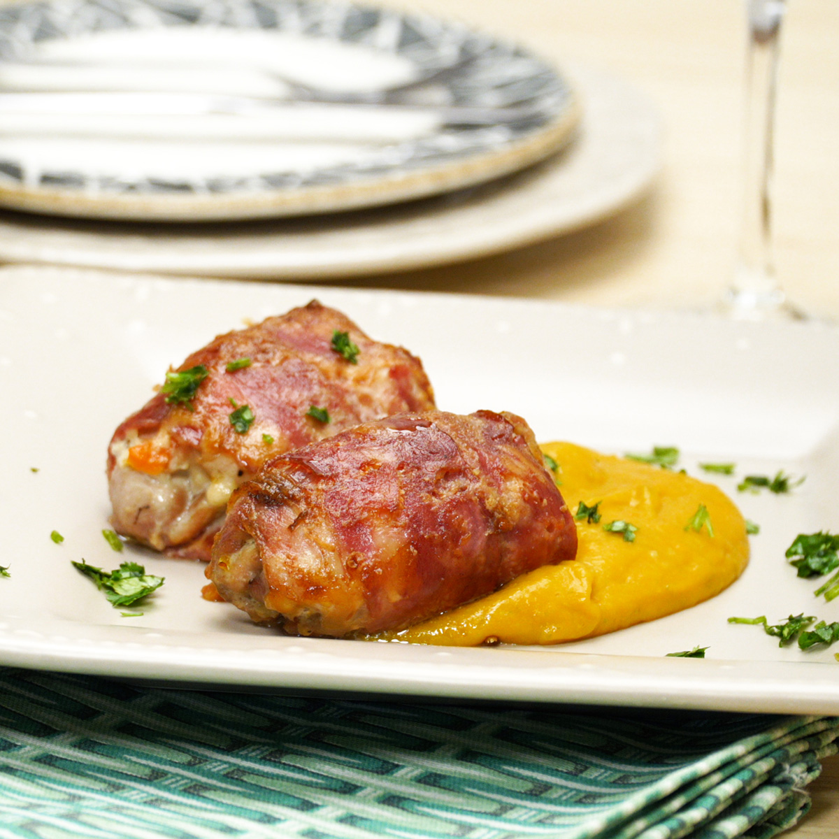 Enroladinhos de frango dourados servidos no prato ao lado do purê de legumes.