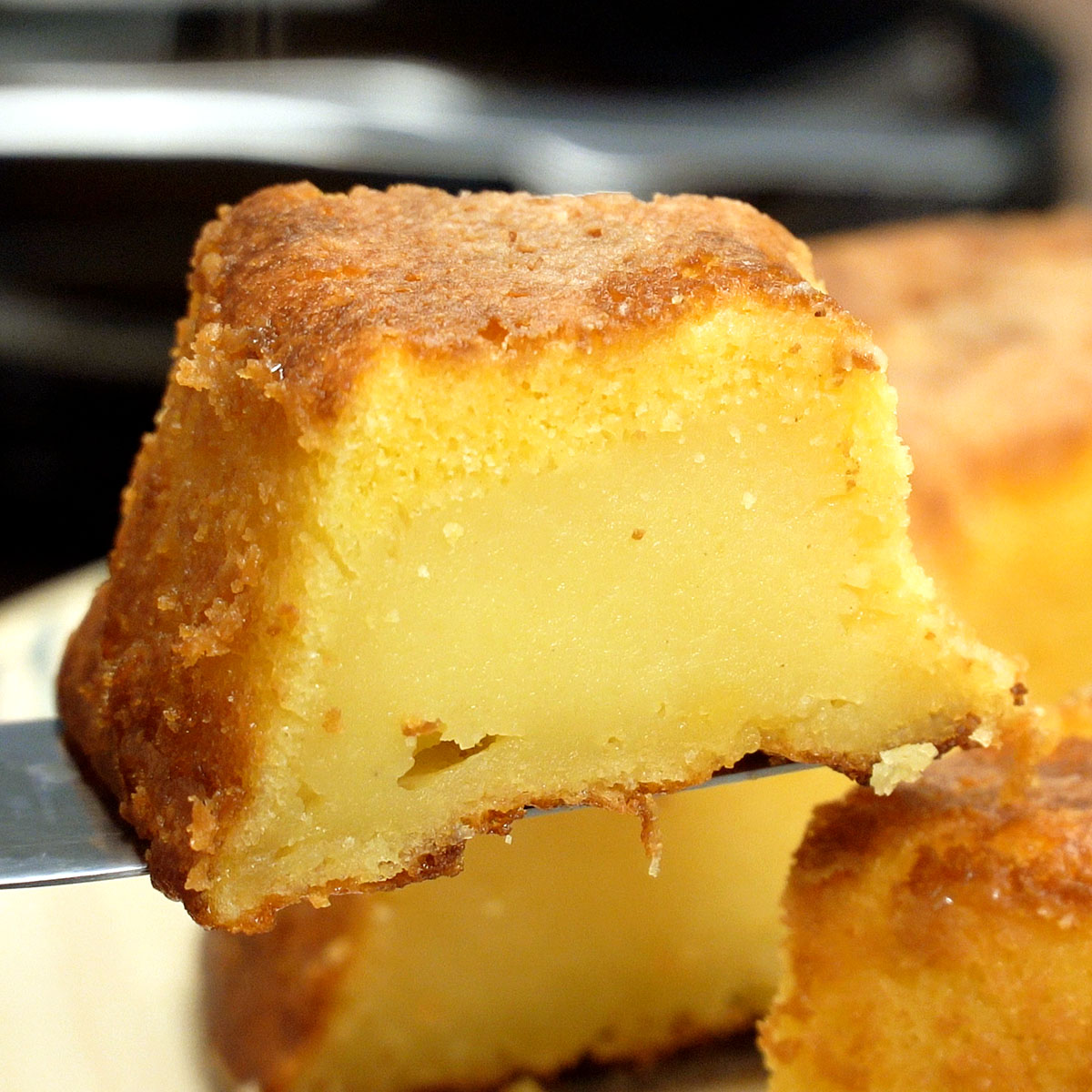 Fatia de bolo de fubá cremoso sendo servido para consumo.