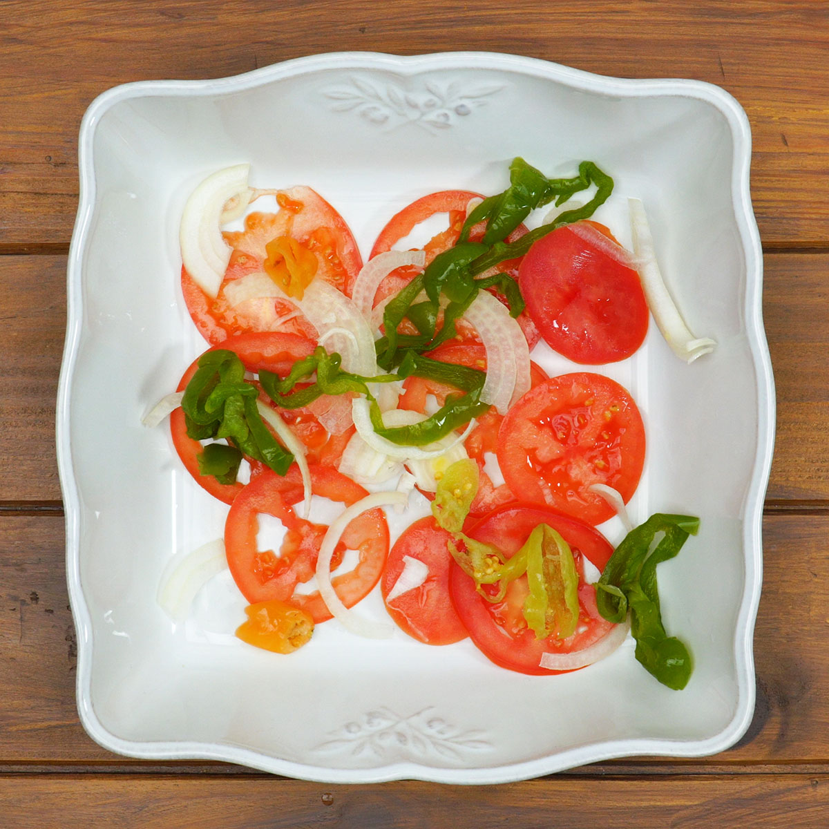 Camada de tomate, cebola e pimentão preparada para receber o peixe.
