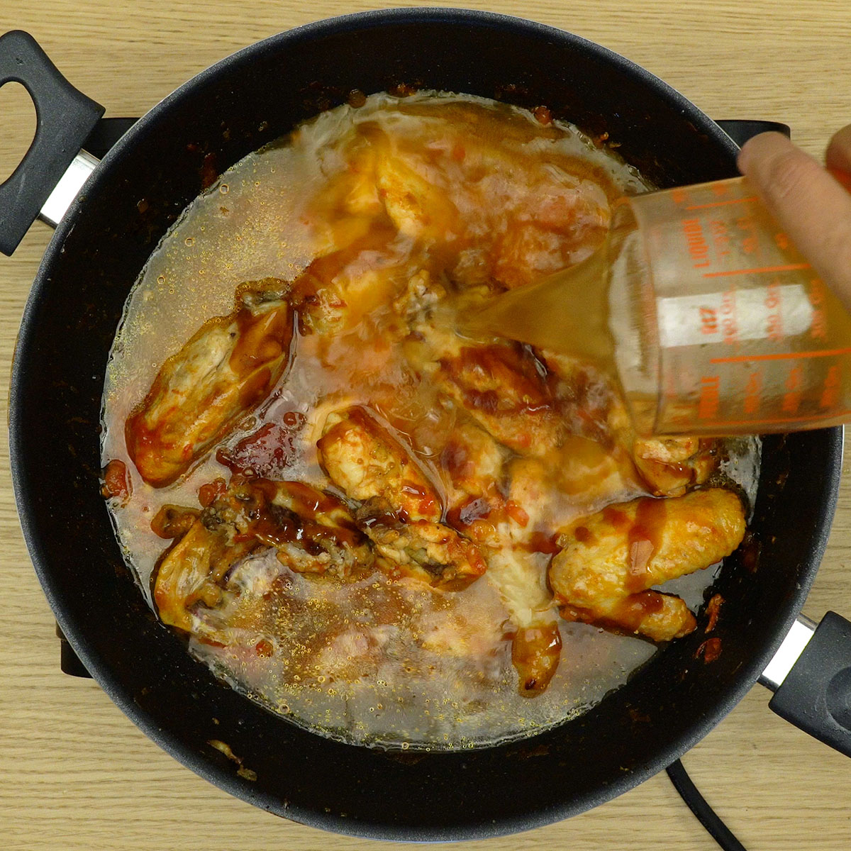 Frango cozinhando em molho agridoce encorpado.