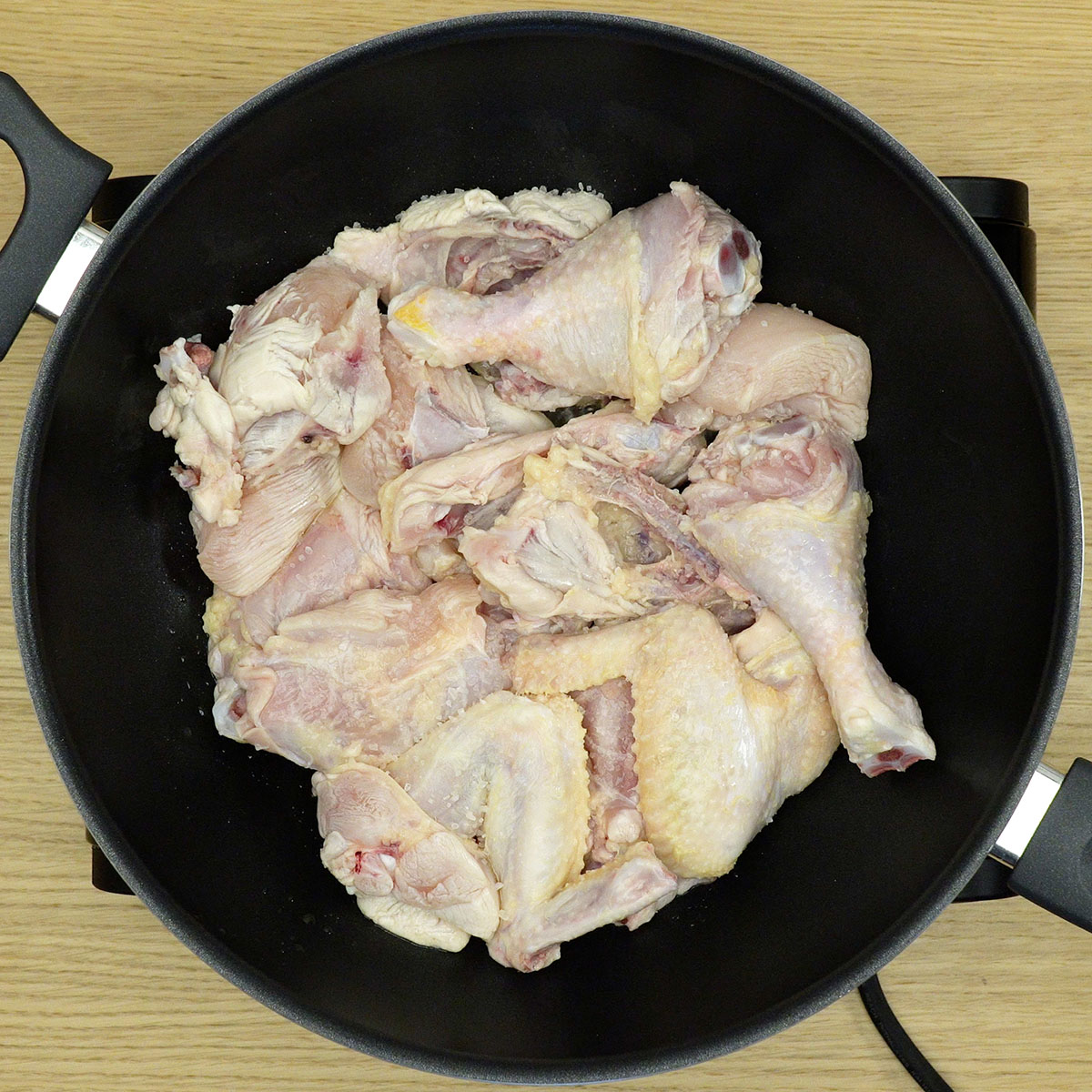 Pedaços de frango dourando na panela para preparar frango com açúcar caramelizado.