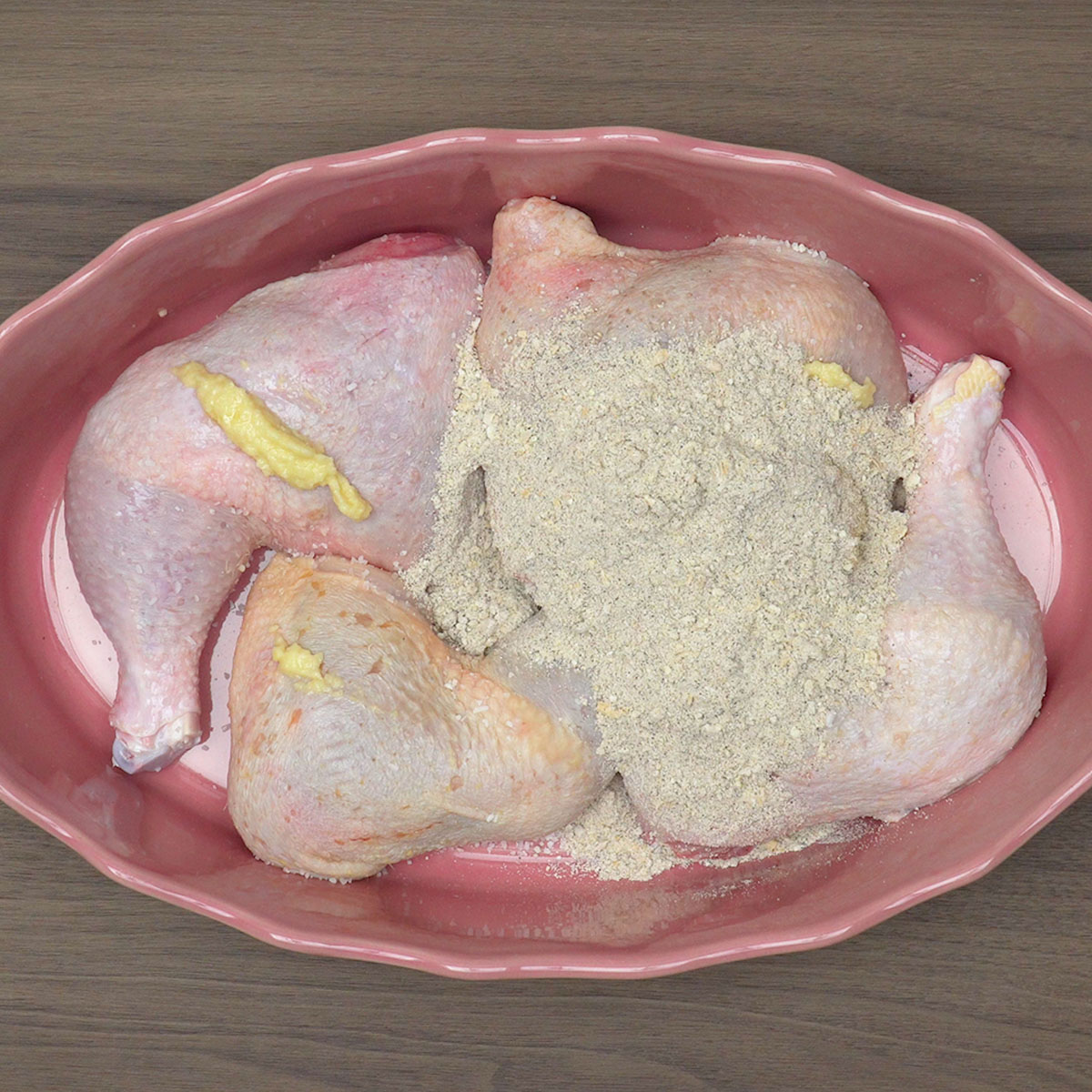Frango sendo temperado com alho, sal e creme de cebola na travessa.