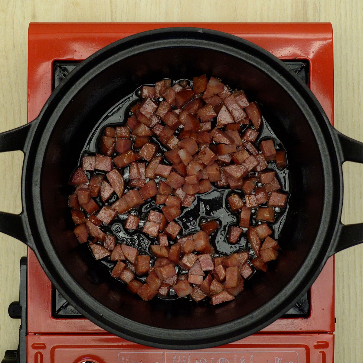 Cubos de linguiça calabresa dourando na panela com azeite.