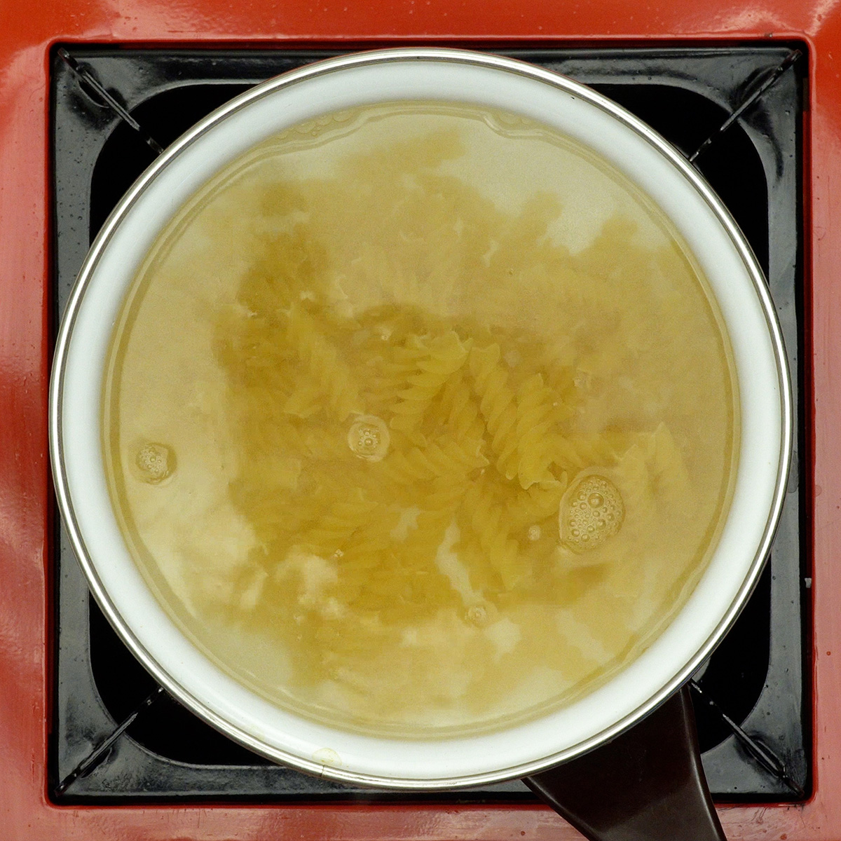 Macarrão parafuso cozinhando em água fervente até atingir o ponto al dente.