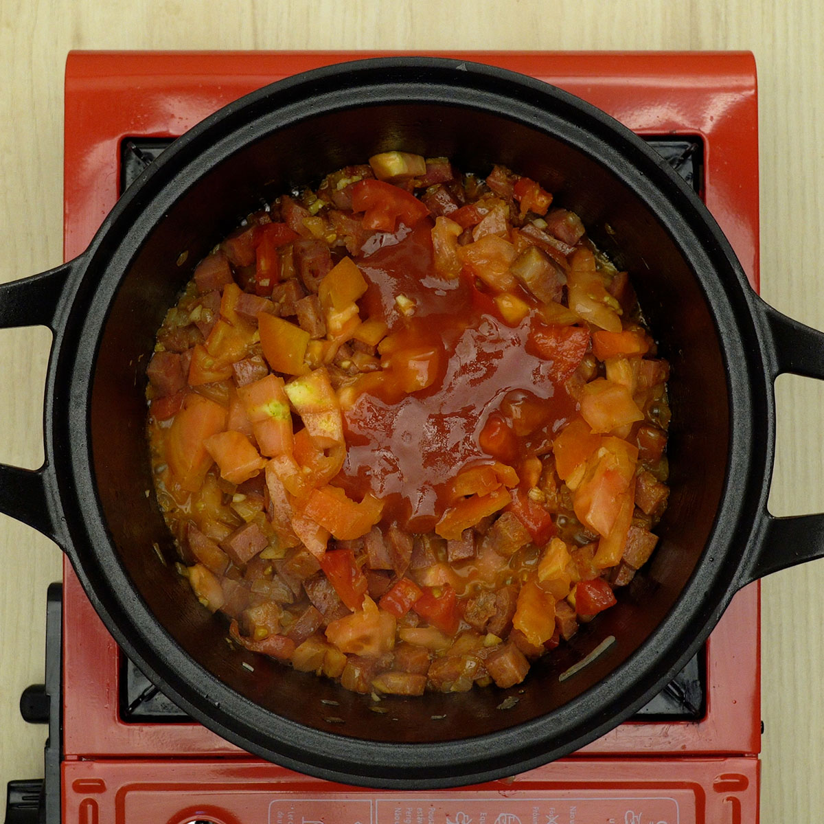 Molho de tomate cozinhando com linguiça calabresa na frigideira.