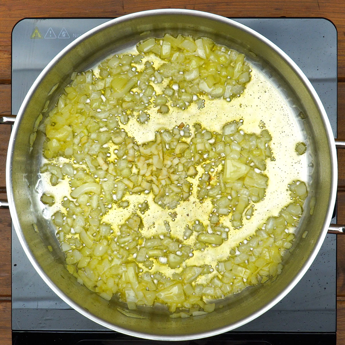 Cebola e alho refogados para recheio de macarrão gratinado com frango.