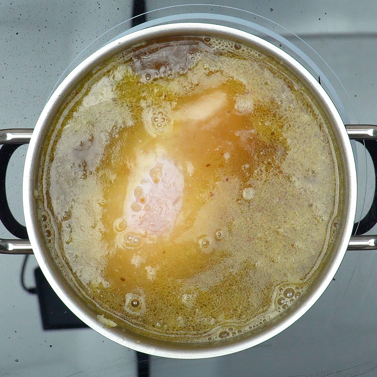 Peito de frango cozinhando com temperos para macarronese cremosa.