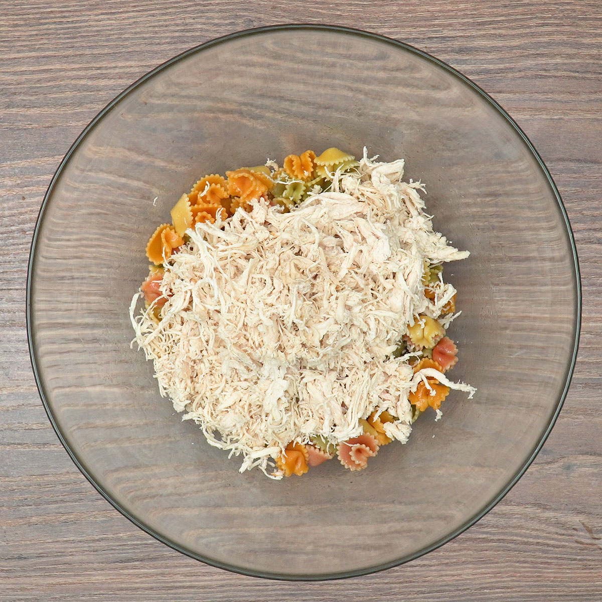 Macarrão e frango sendo misturados em tigela para preparar macarronese.