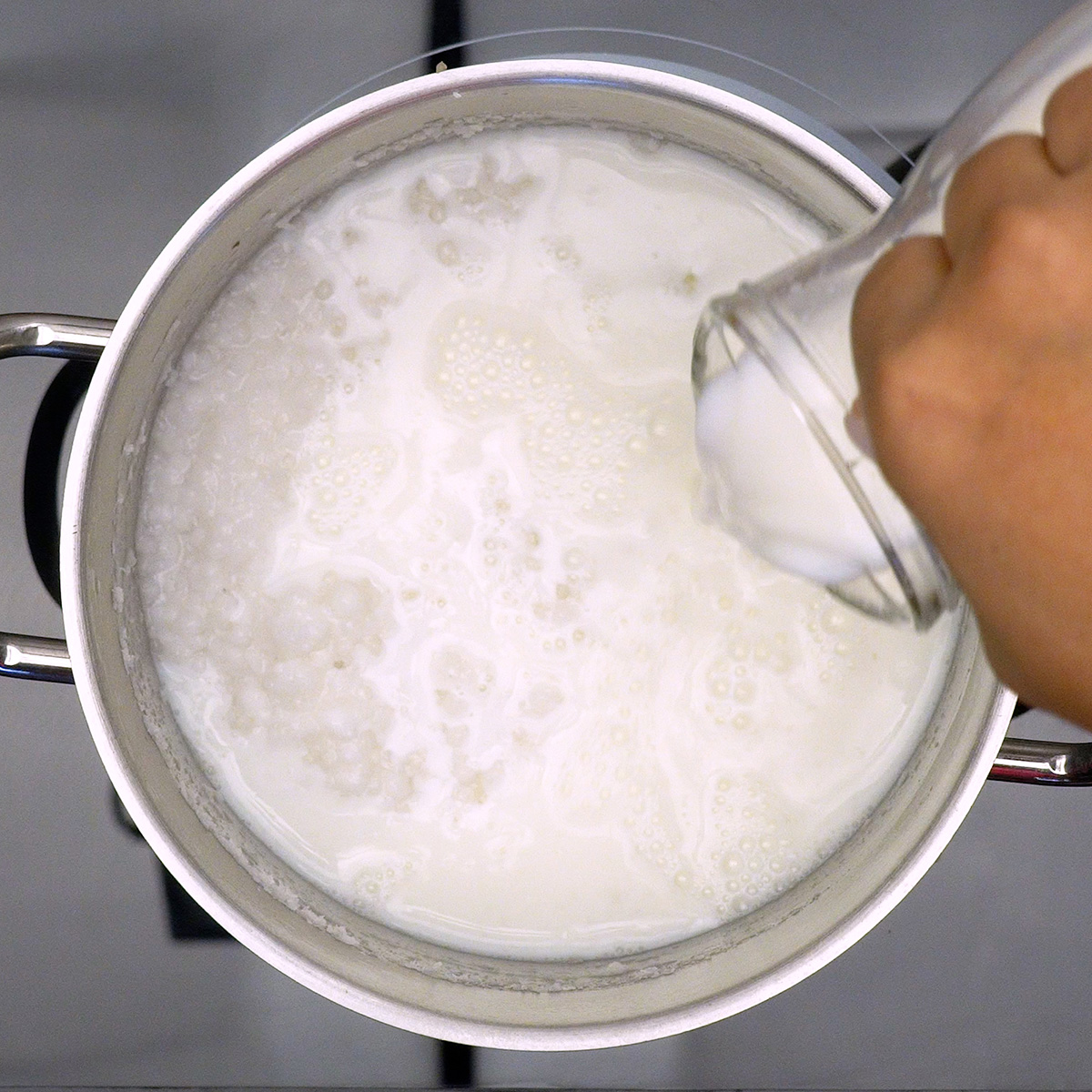 Leite sendo adicionado à tapioca para formar a base cremosa do mingau.