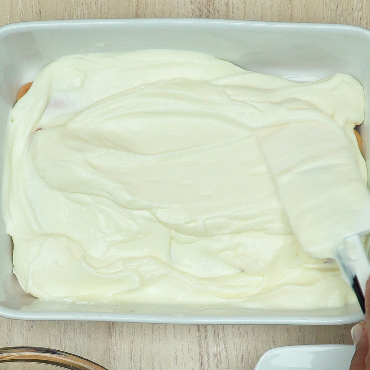 Creme de limão espalhado sobre os biscoitos na travessa.