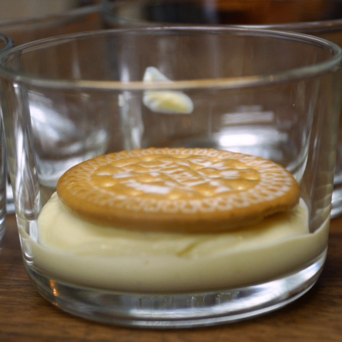 Camada de biscoitos Maria sobre creme de maracujá no copinho