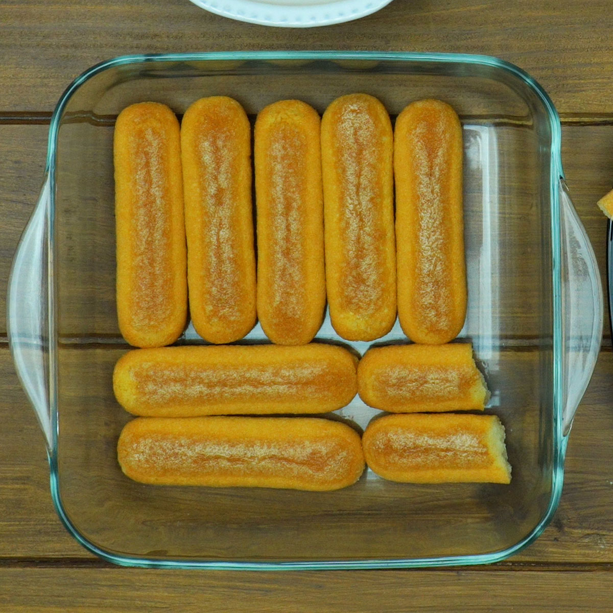 Biscoitos champanhe umedecidos formando a primeira camada do pavê.