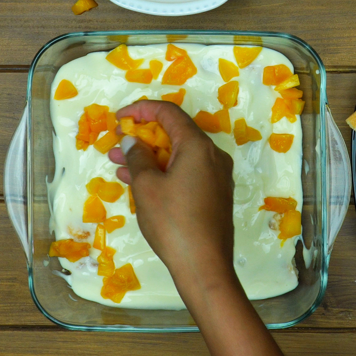 Camada de creme coberta com pedaços de pêssego em calda.