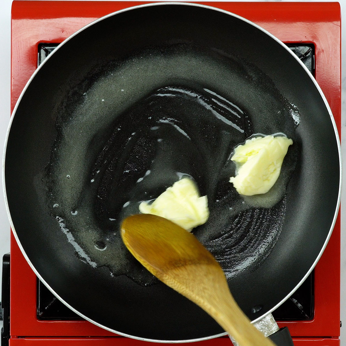 Manteiga derretendo em frigideira para preparar peito de frango ao alho.