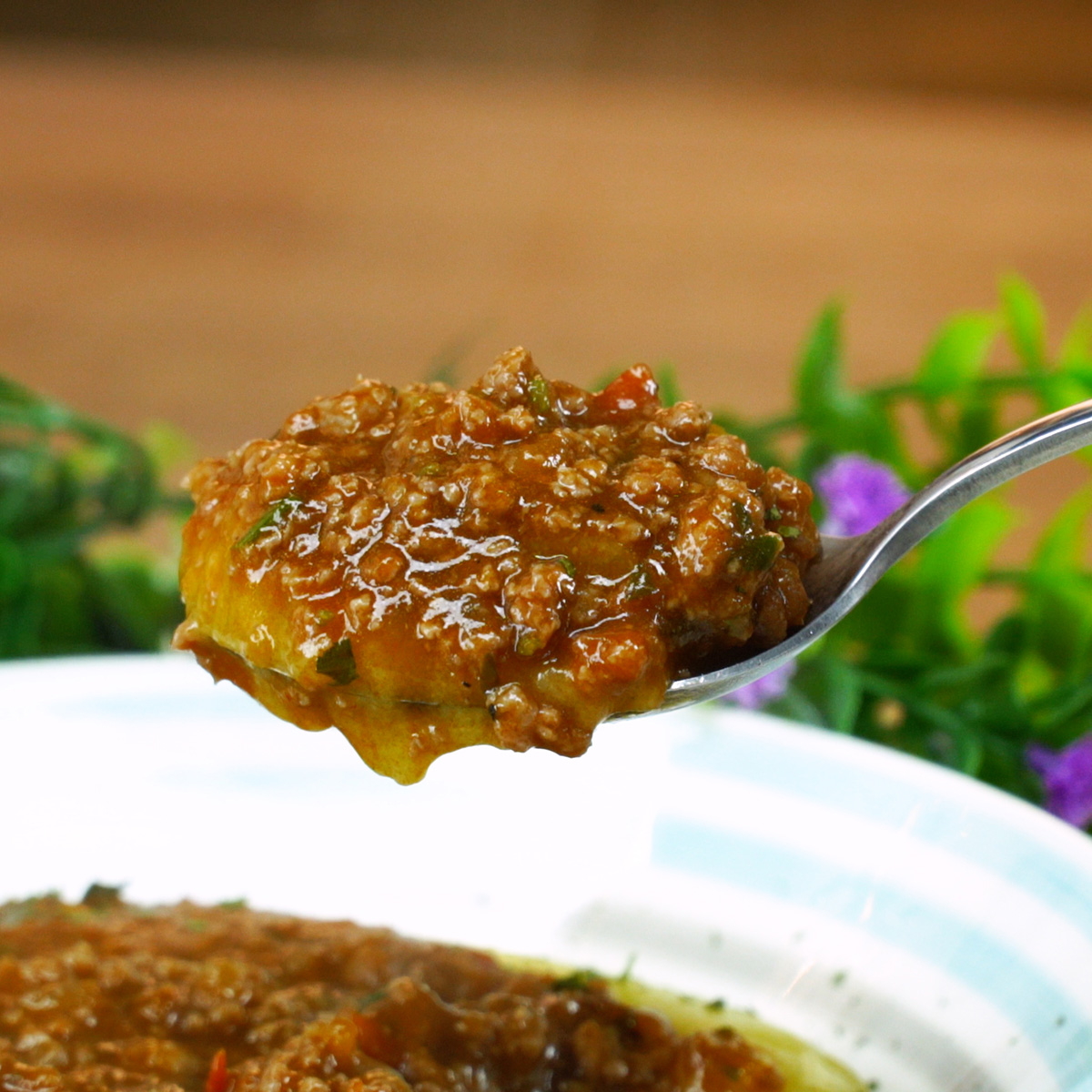 Polenta cremosa servida com molho de carne moída sendo provado.