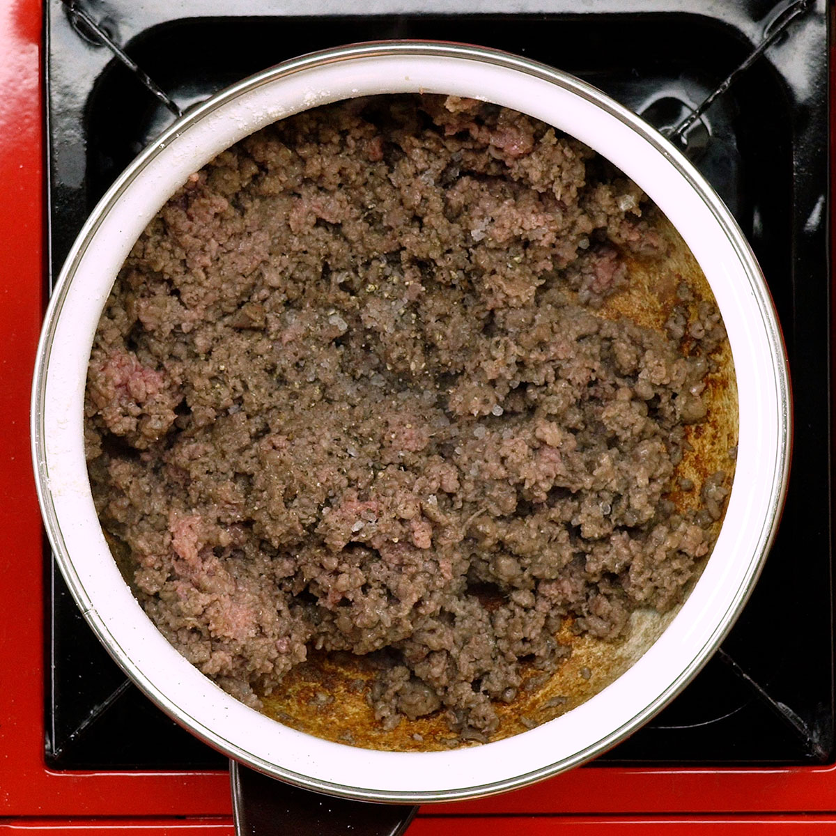 Carne moída dourando na panela com azeite e temperos.