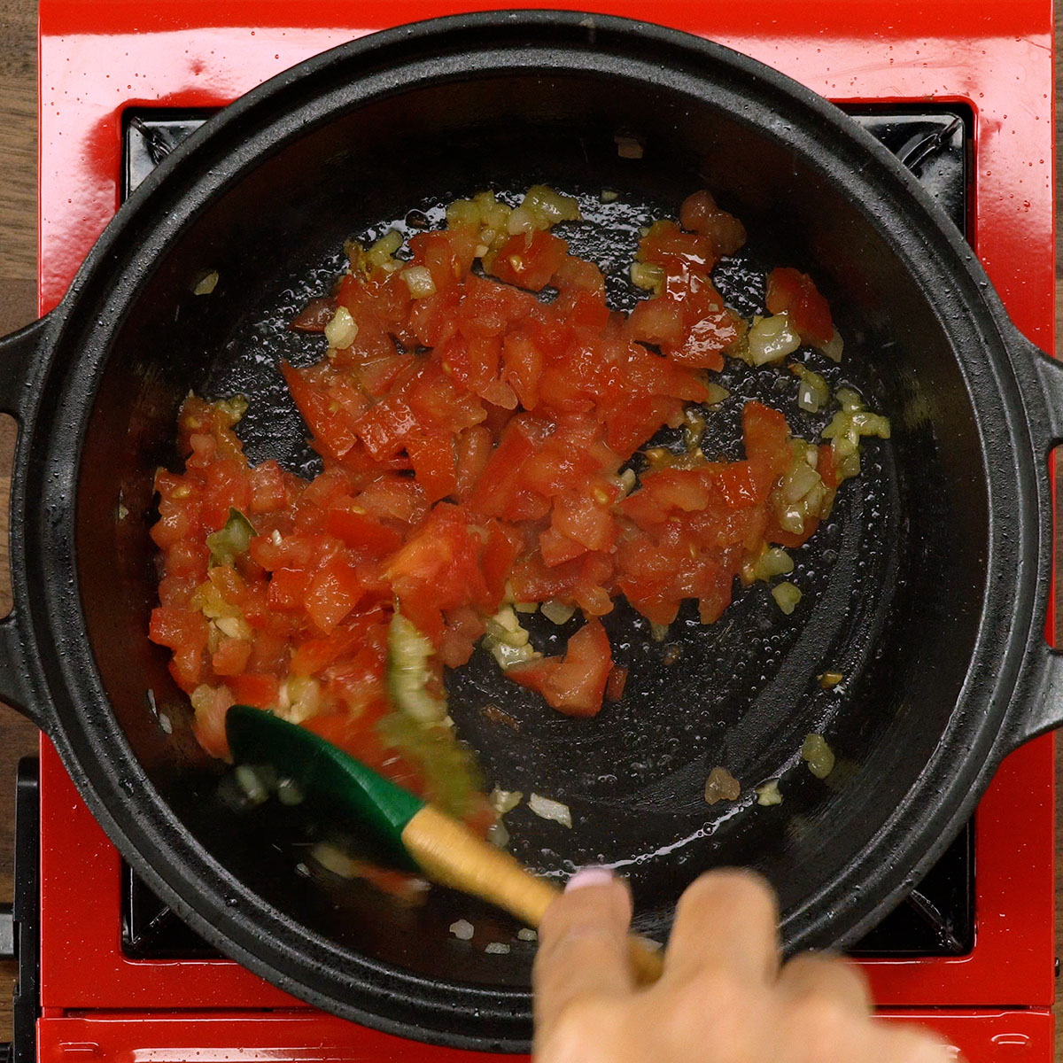 Cebola, alho, louro e tomates refogando na panela.