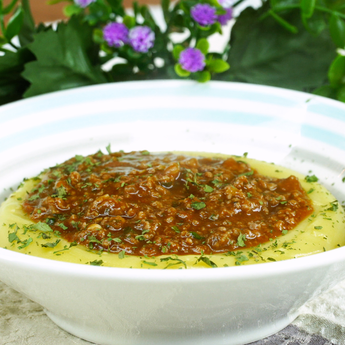 Polenta cremosa servida com molho de carne moída e salsinha.