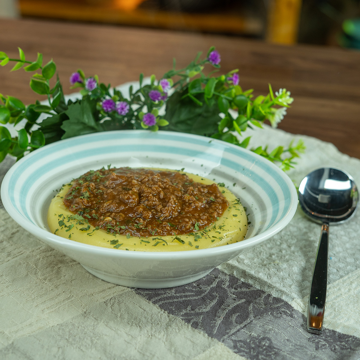 Empratamento polenta cremosa servida com molho de carne moída finalizado com salsinha.