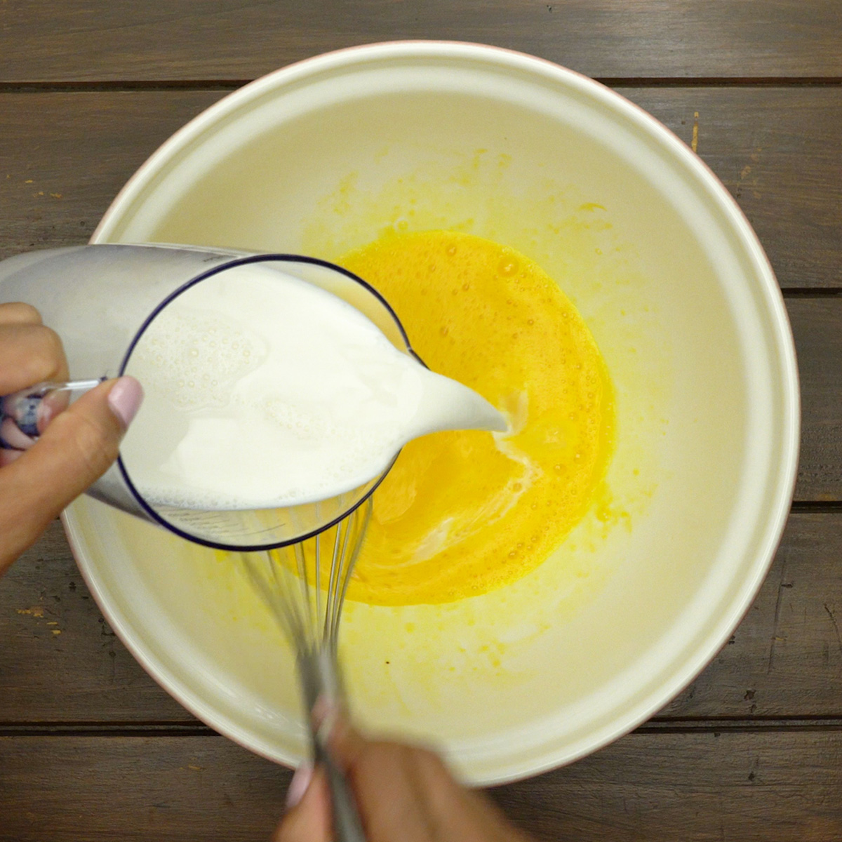 Leite sendo misturado aos ovos para preparar o creme das rabanadas.