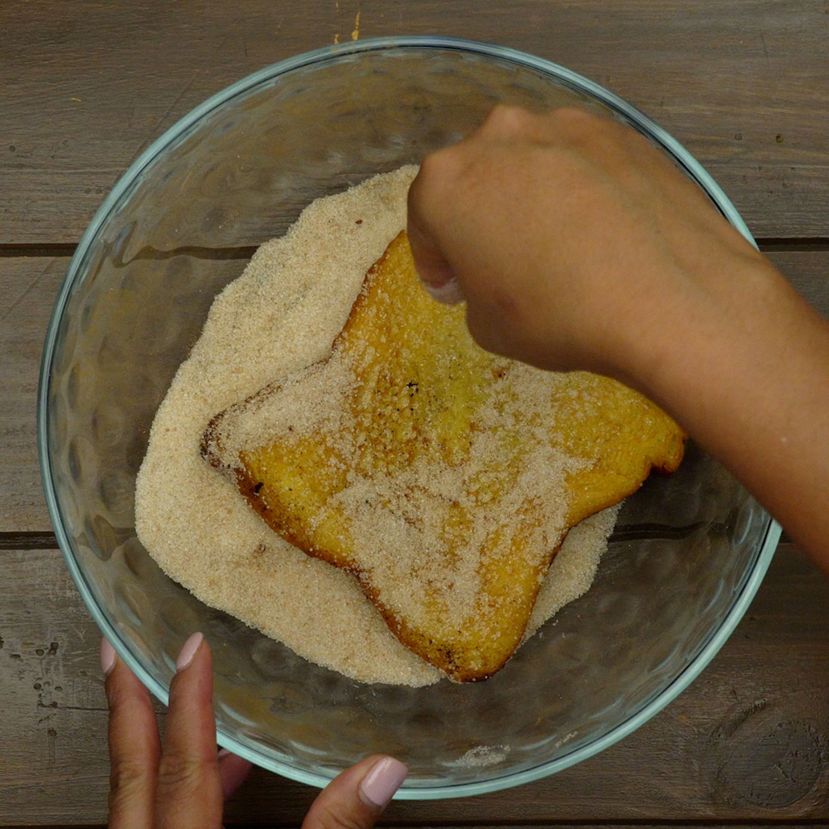 Rabanadas sendo cobertas com açúcar e canela após a fritura.