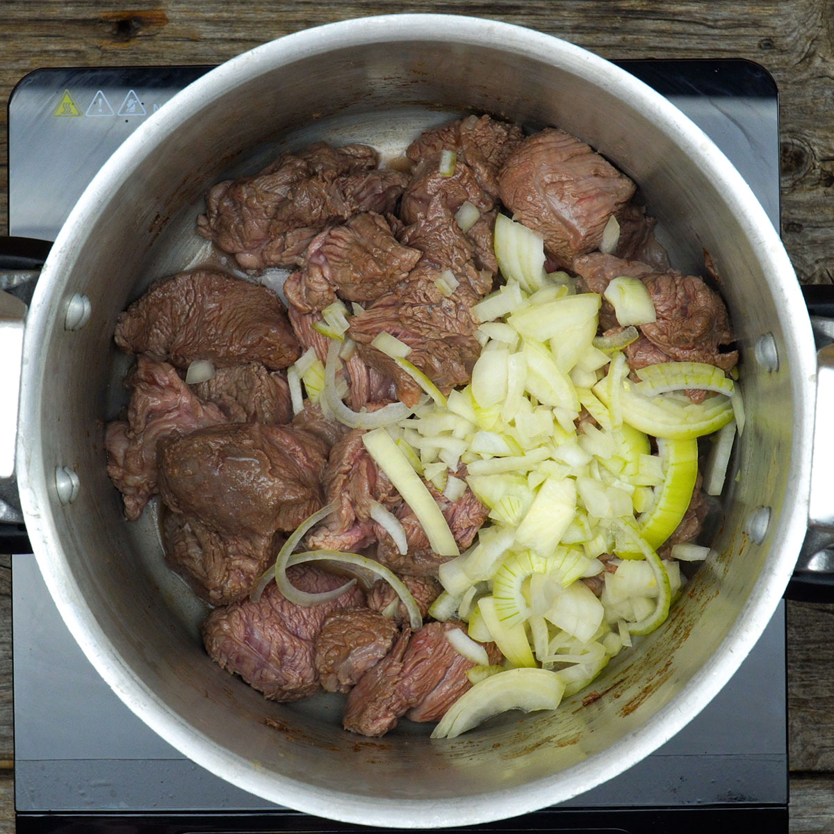 Cebola e alho sendo refogados com carne para preparar ragu de carne com polenta cremosa.