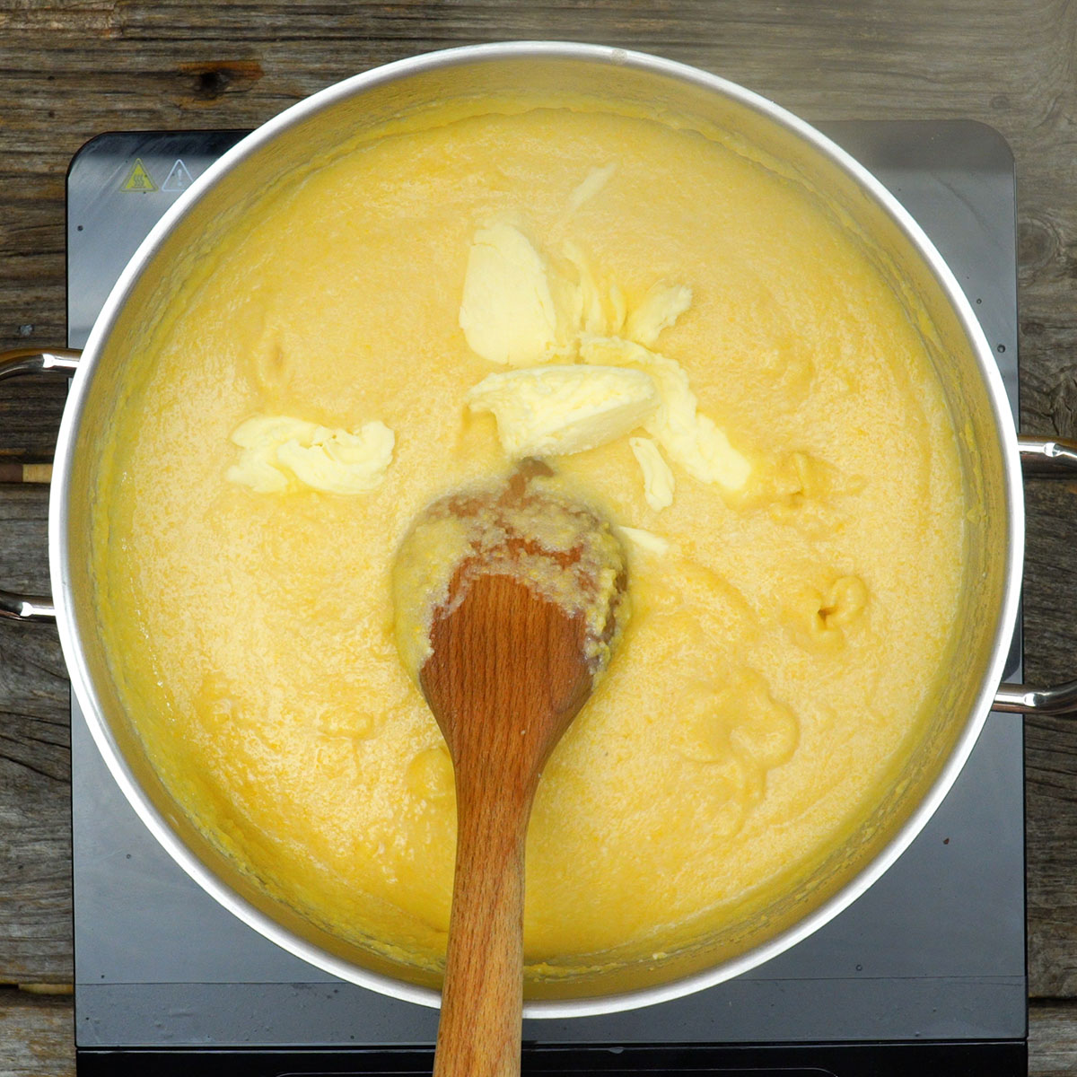 Polenta cremosa finalizada com manteiga pronta para servir.