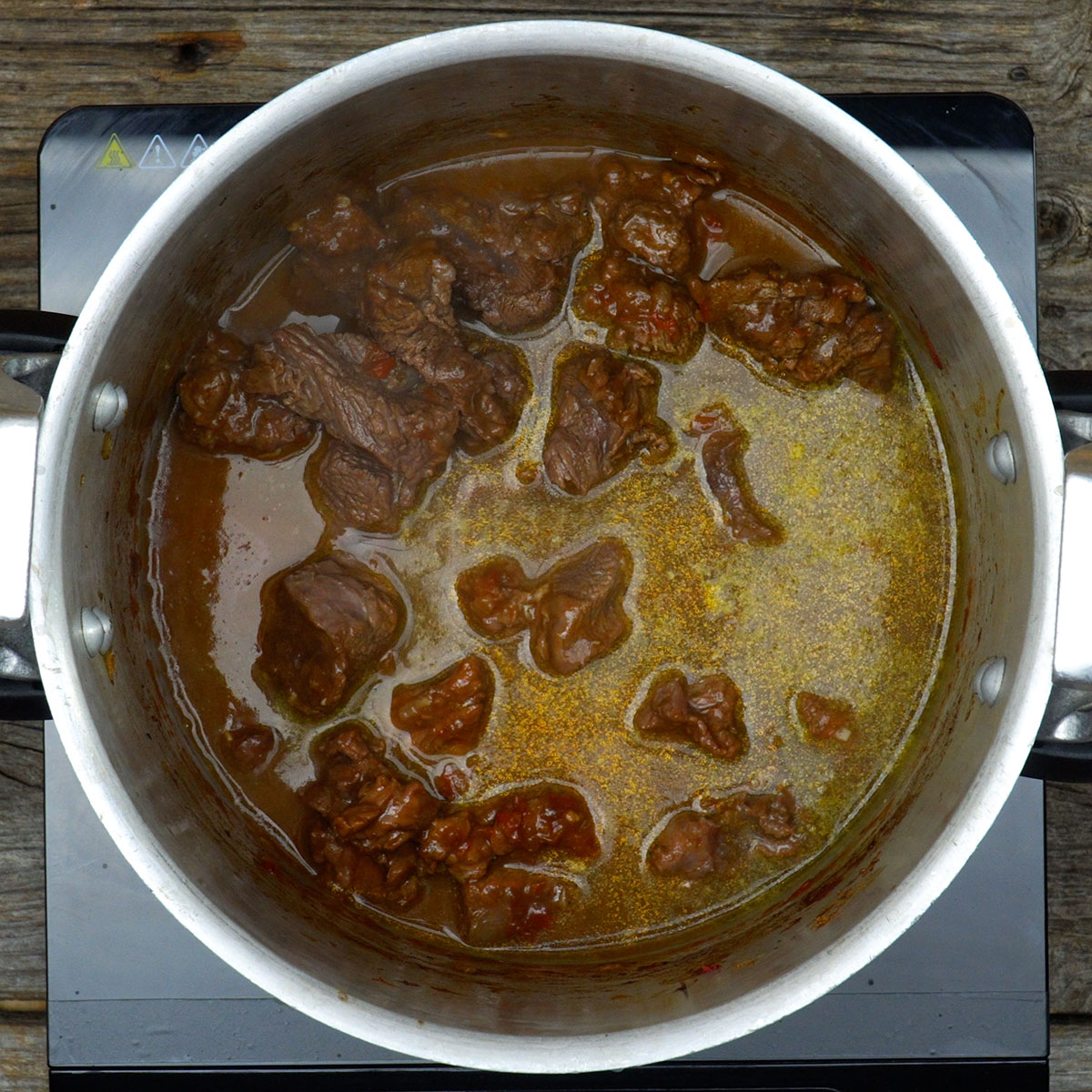 Molho do ragu sendo preparado com vinho tinto, caldo de carne e extrato de tomate.