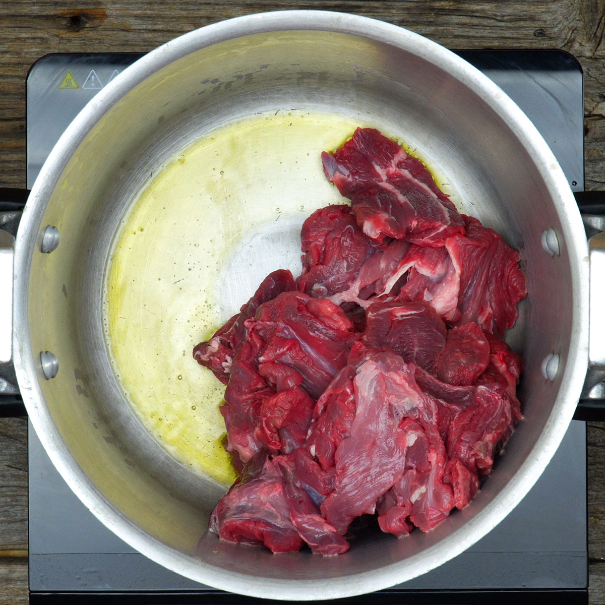 Cubos de carne sendo selados em panela para preparar ragu de carne com polenta cremosa.
