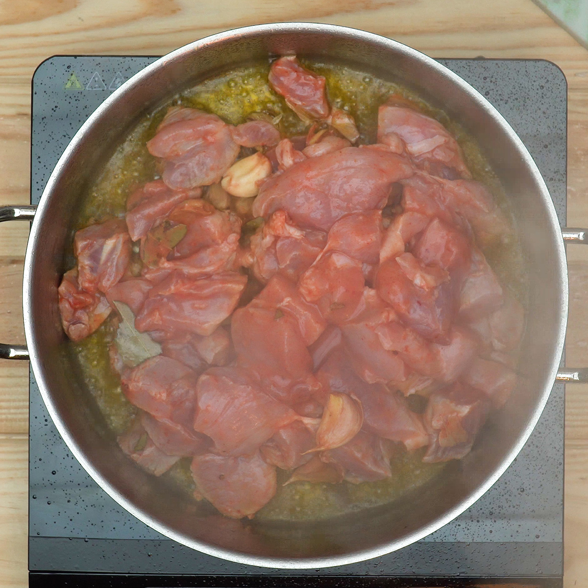 Carne de porco com marinada sendo adicionada à frigideira para cozinhar.