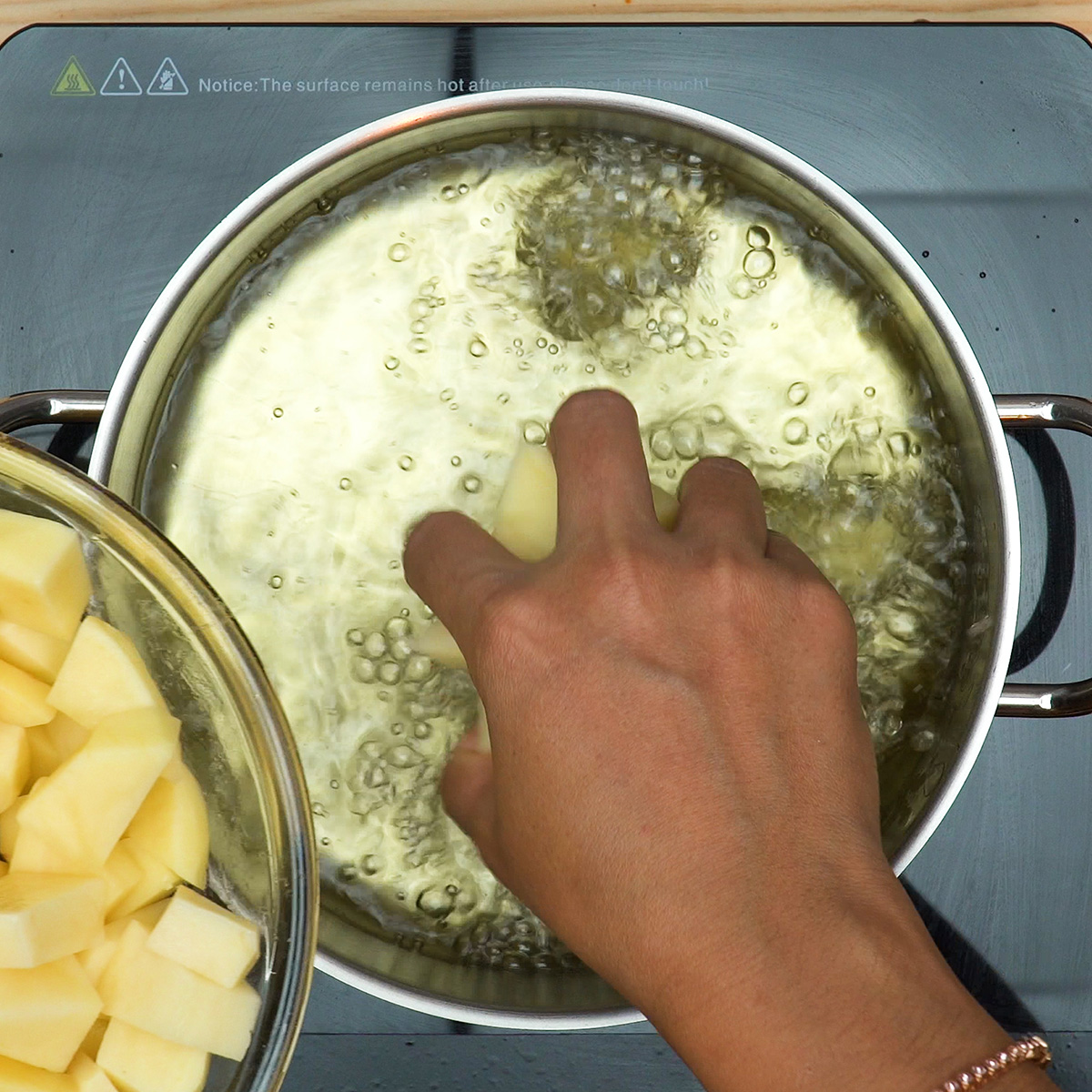 Batatas cortadas em cubos a fritar em óleo quente e a escorrer sobre papel-toalha para acompanhar os rojões.