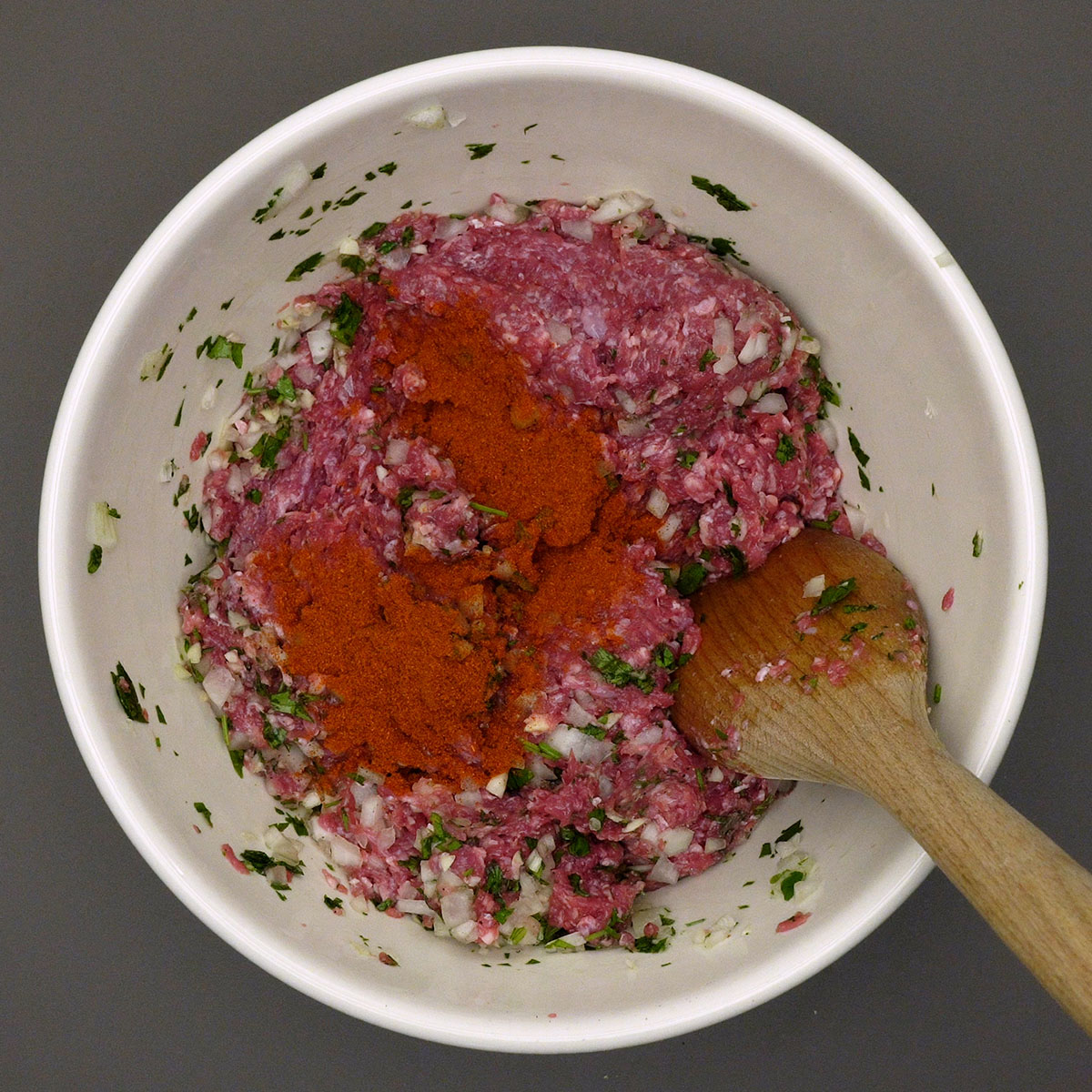Páprica sendo incorporada à carne moída temperada para preparar os rojões.