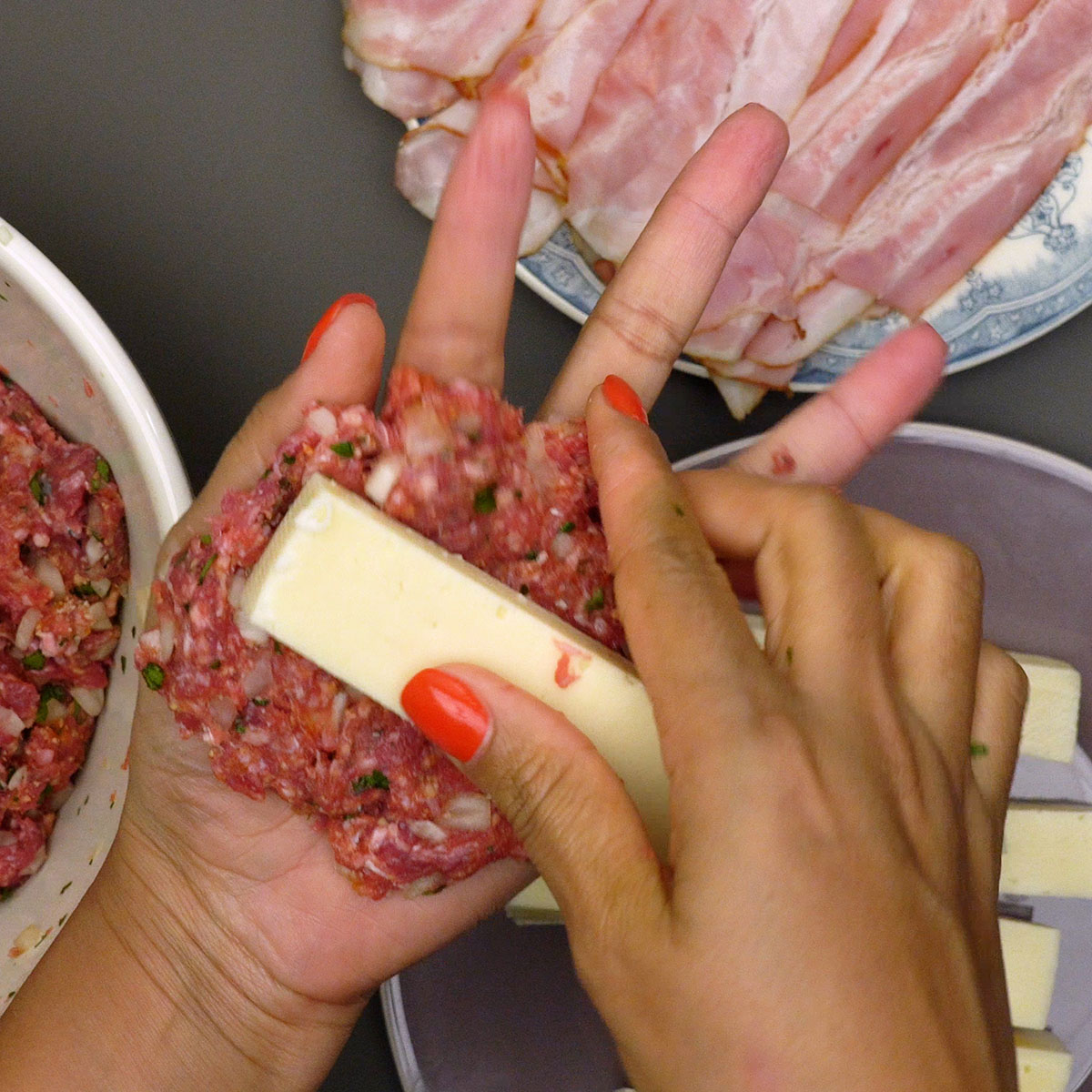 Carne moída sendo moldada ao redor de palitos de queijo muçarela.