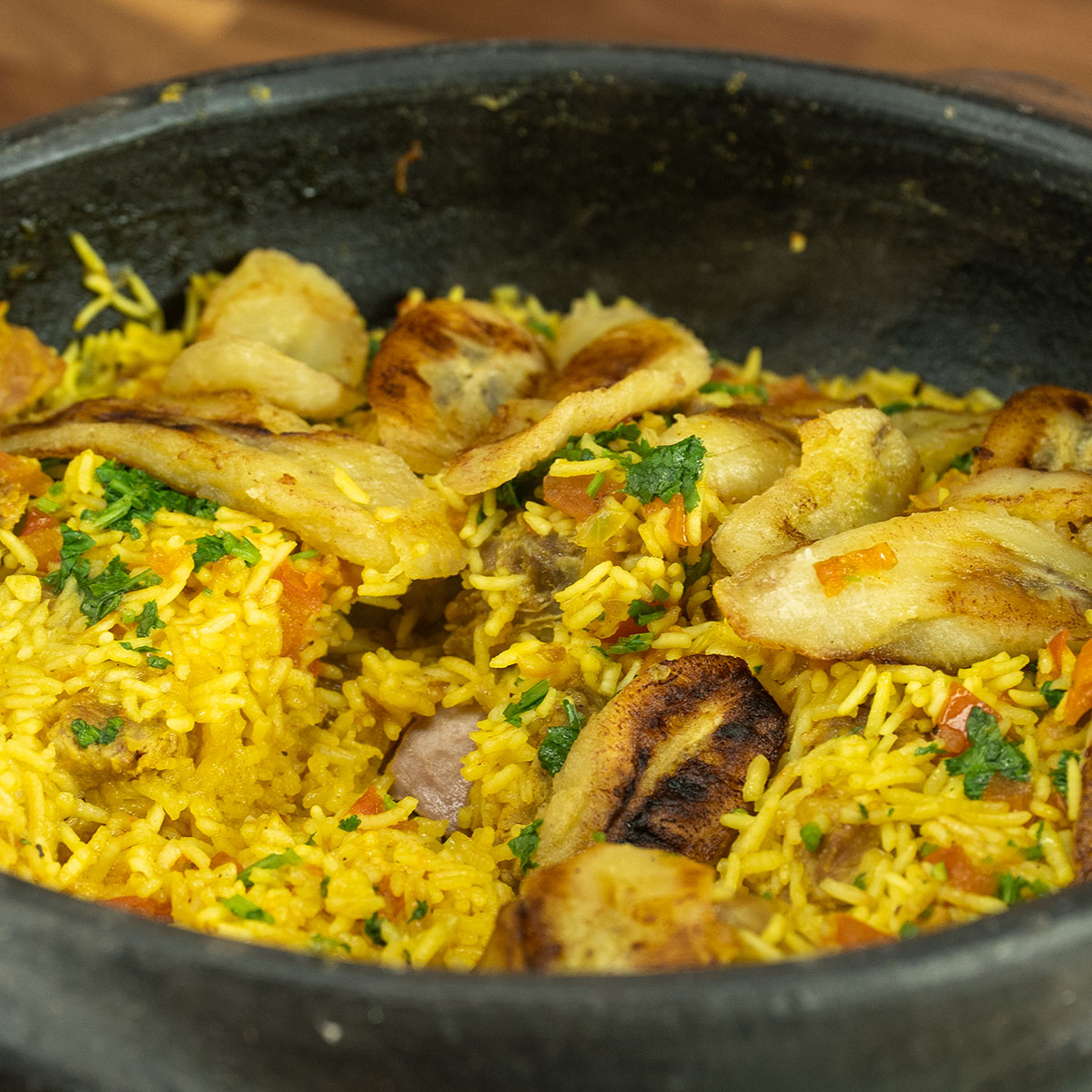 Tacho com arroz de porco com banana frita pronto para ser servido.