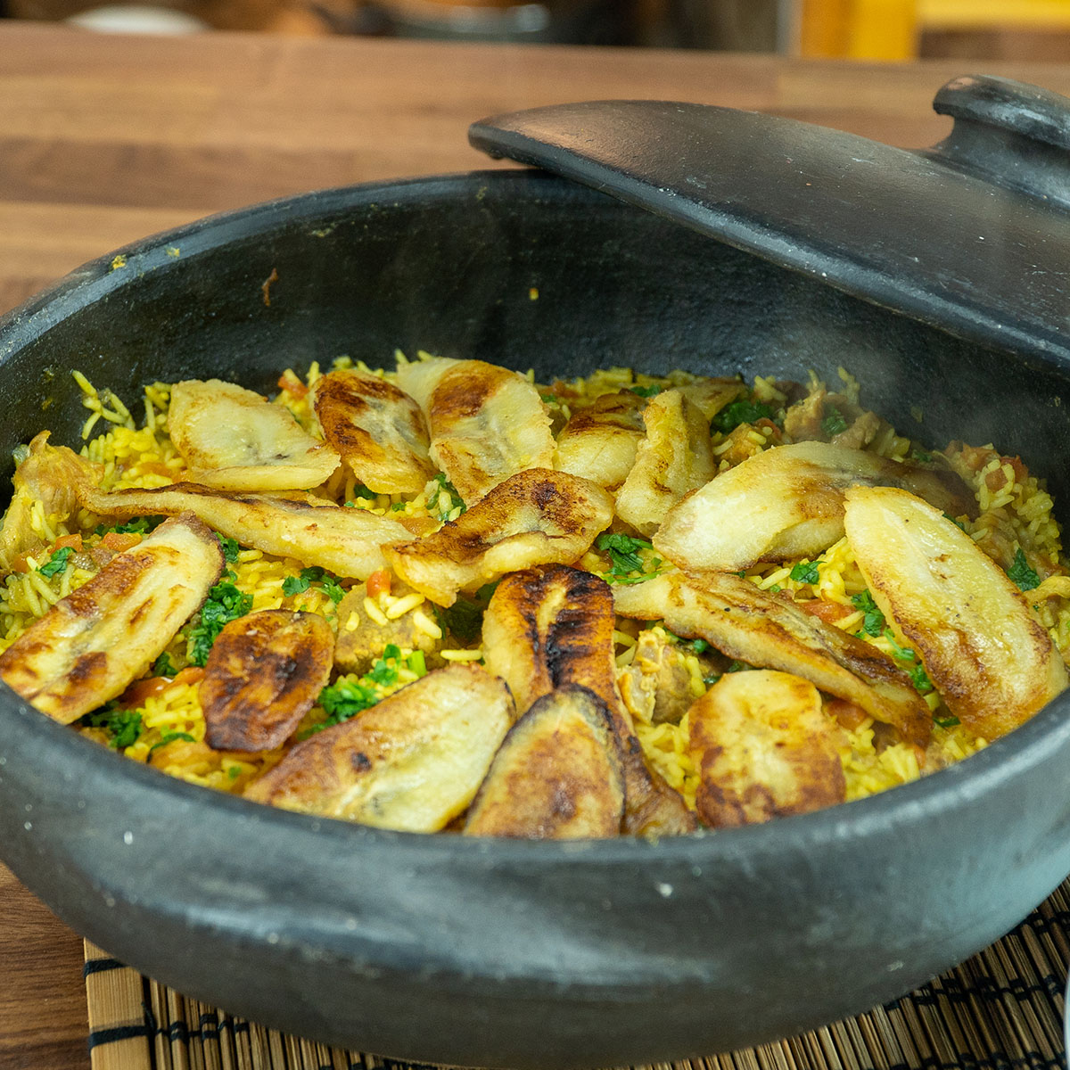 Tacho com arroz de porco com banana frita pronto para ser servido.