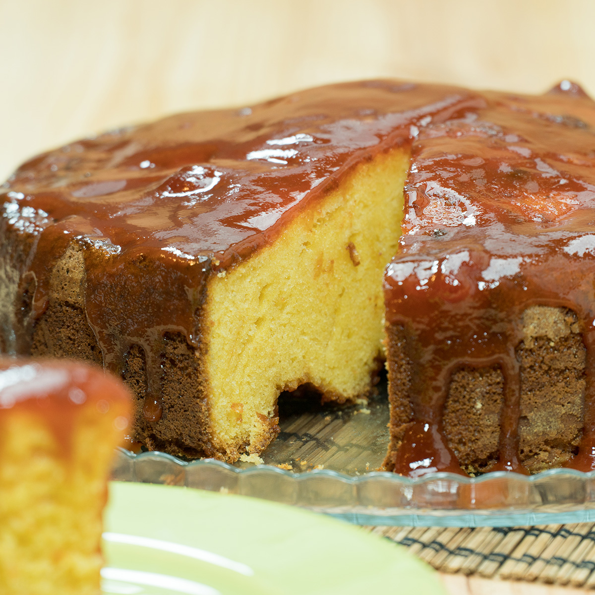 Bolo de fubá com goiabada finalizado com calda de goiabada sendo servida.