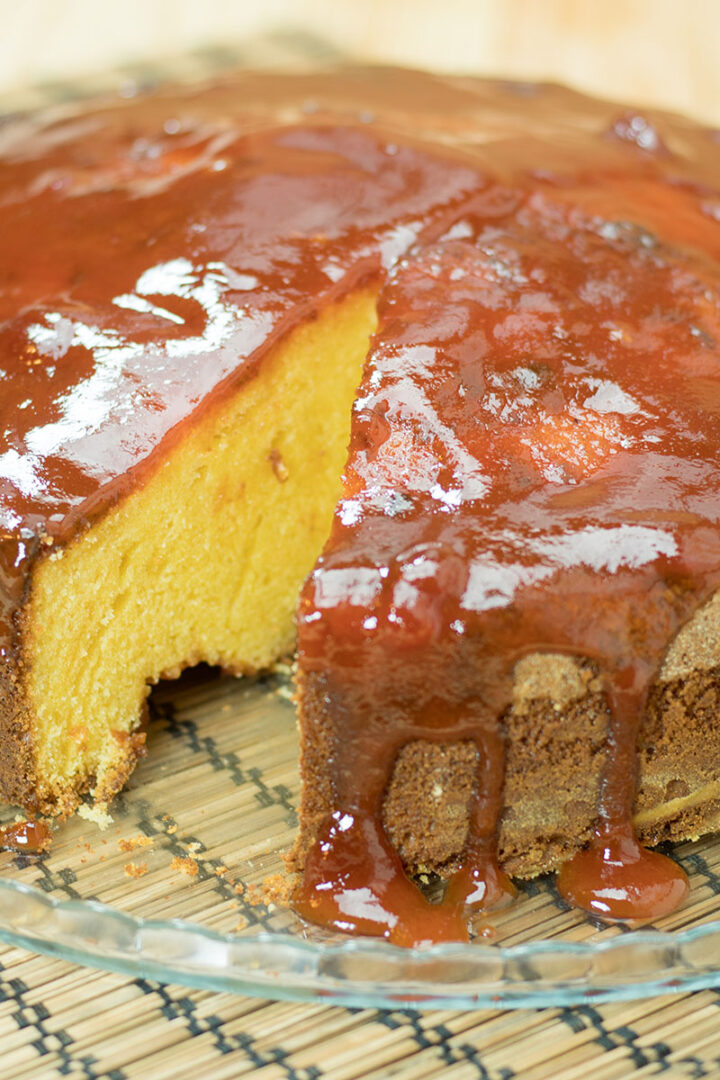 Bolo de fubá com goiabada finalizado com calda de goiabada sendo servida.