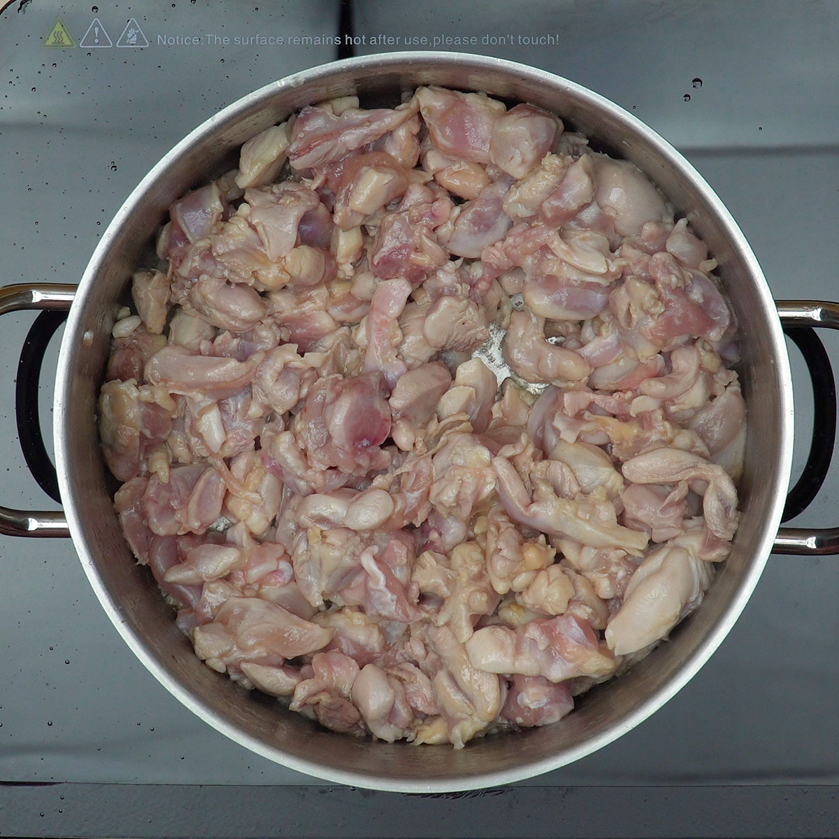 Pernas e sobrecoxas de frango dourando em panela com azeite quente.