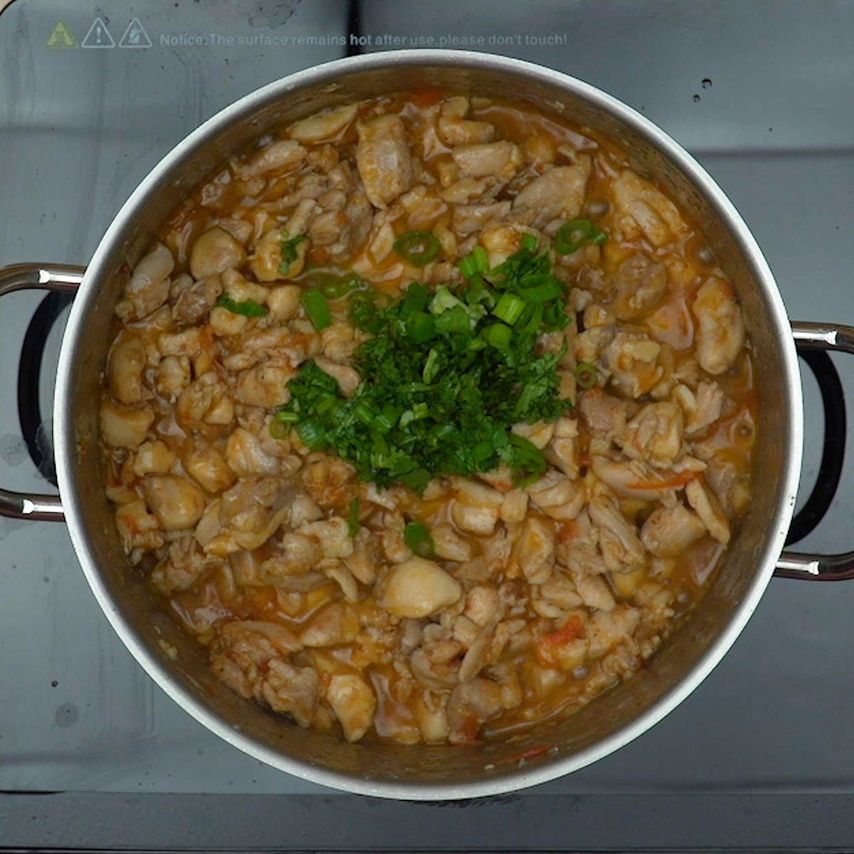 Frango cozinhando lentamente no caldo temperado com tomate e cebola.